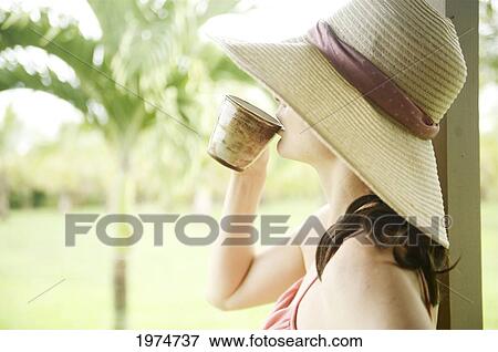 Stock Photo - Hawaii, Kauai, Portrait Of A Beautiful Woman In A Pink Sundress Drinking Tea.. Fotosearch