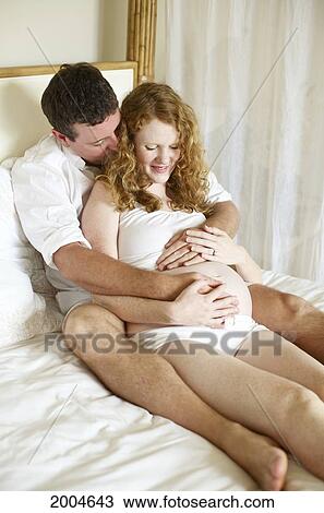 Stock Image - Hawaii, Kauai, Princeville, A Mother And Father To Be Hold Eachother In Bed.. Fotosearch