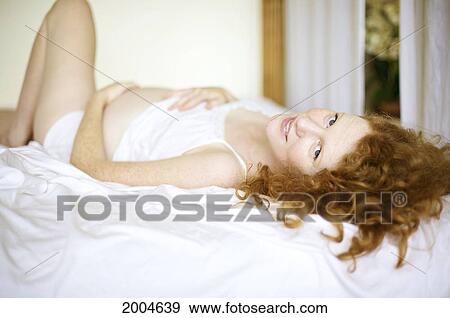 Hawaii, Kauai, Princeville, A Mother To Be Lays On Bed Holding Her Belly. View Large Photo Image Stock Photo - Hawaii, Kauai, Princeville, A Mother To Be Lays On Bed Holding Her Belly.. Fotosearch