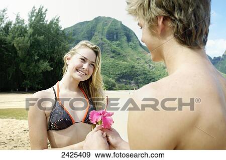 Hawaii, Kauai, Tunnels Beach, a young man presents a flower to a beautiful girl. View Large Photo Image Stock Photo - Hawaii, Kauai, Tunnels Beach, a young man presents a flower to a beautiful girl.. Fotosearch