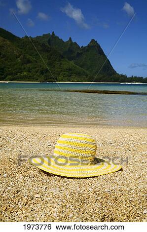 Stock Photograph - Hawaii, Kauai, Tunnels Beach, Still Life Of A Yellow Straw Hat On The Beach.. Fotosearch