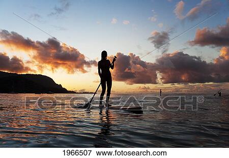 Stock Photo - Hawaii, Kauai, Woman Stand Up Paddling In Ocean, Beautiful Sunset.. Fotosearch