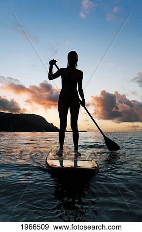 Stock Photo - Hawaii, Kauai, Woman Stand Up Paddling In Ocean, Beautiful Sunset.. Fotosearch