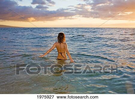 Hawaii, Kauai, Woman Walking In The Ocean As The Sun Sets. View Large Photo Image Stock Photo - Hawaii, Kauai, Woman Walking In The Ocean As The Sun Sets.. Fotosearch