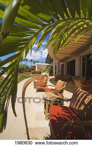 Stock Image - Hawaii, Lanai, Four Seasons Manele Bay Hotel, Luxurious Outdoor Lounge Area, Palm Frond Overhead.. Fotosearch