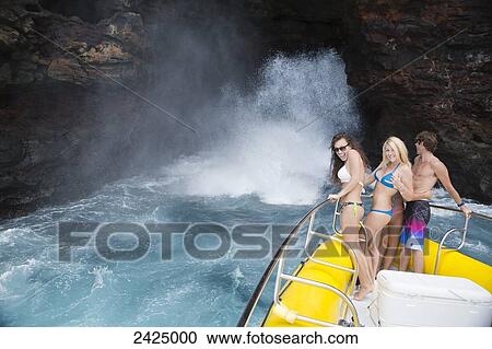 Hawaii, Lanai, Group of friends on a boating tour, Water spraying from sea cave. View Large Photo Image Stock Image - Hawaii, Lanai, Group of friends on a boating tour, Water spraying from sea cave.. Fotosearch
