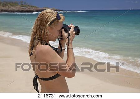 Stock Image - Hawaii, Lanai, Hulopoe, A female tourist photographs the ocean.. Fotosearch
