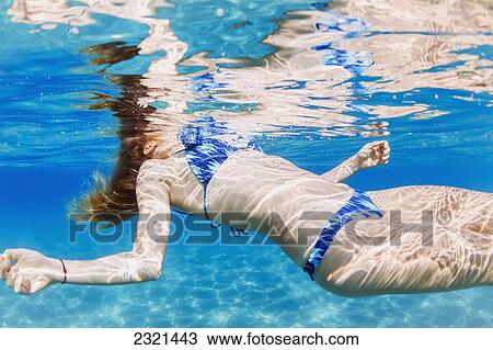 Stock Image - Hawaii, Lanai, Manele Bay, Young Woman Floating At Oceans Surface.. Fotosearch