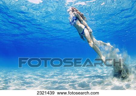 Stock Photo - Hawaii, Lanai, Manele Bay, Young Woman Swimming Toward Ocean Surface Trailing Sand Behing Her.. Fotosearch