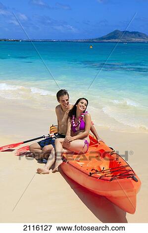Stock Photo - Hawaii, Lanikai, A young couple with their kayak on the beach.. Fotosearch