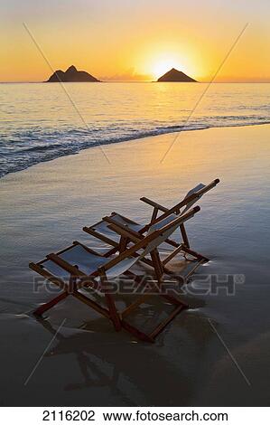 Stock Image - Hawaii, Lanikai, Empty beach chair at sunset.. Fotosearch
