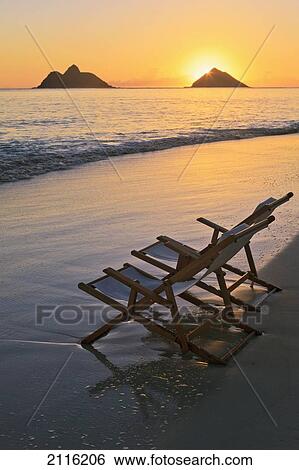 Stock Photograph - Hawaii, Lanikai, Pair of empty beach chairs at sunset.. Fotosearch