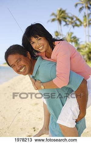 Stock Image - Hawaii, Local Couple Being Playful On A Tropical Beach.. Fotosearch
