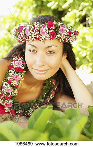 Stock Photo - Hawaii, Local Girl Laying On Sand Wearing Flower Leis Surrounded By Bright Vegetation.. Fotosearch