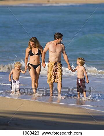 Stock Image - Hawaii, Maui, Baldwin Beach, A Young Family Walking Along The Waters Edge.. Fotosearch