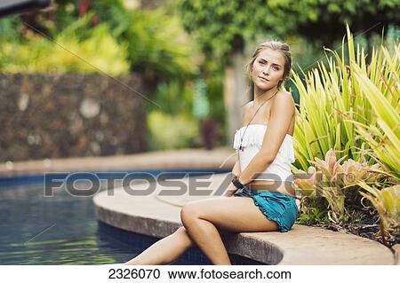 Stock Image - Hawaii, Maui, Beautiful Young Blond Woman Relaxing Poolside.. Fotosearch