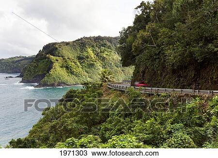 Stock Image - Hawaii, Maui, Car Traveling Along The Cliffs Of Road To Hana.. Fotosearch