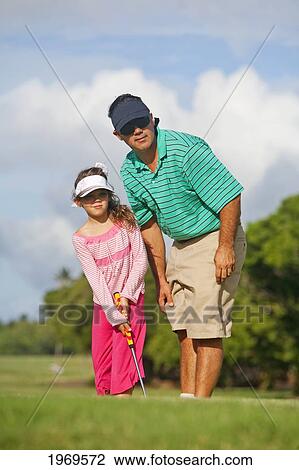 Stock Image - Hawaii, Maui, Father Teaching Daughter How To Play Golf On The Putting Green.. Fotosearch