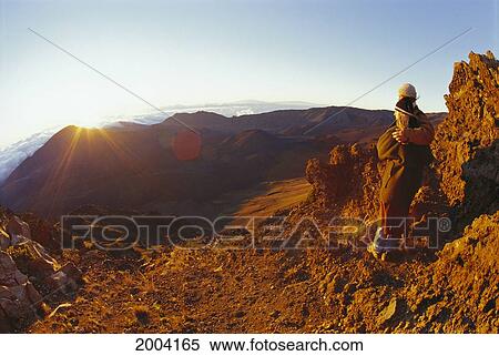 Stock Photography - Hawaii, Maui, Haleakala Crater, Couple Embrace At Summit Watch Sunrise Stand On Rim Bright Sunlight Sunrays. Fotosearch