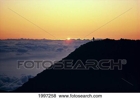 Stock Photo - Hawaii, Maui, Haleakala Crater, Person In Distance Watching Sunrise, Above Clouds A46D. Fotosearch