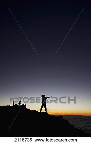 Stock Photography - Hawaii, Maui, Haleakala, The silhouette of a man posing on summit at sunset.. Fotosearch