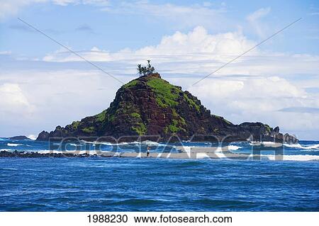 Stock Image - Hawaii, Maui, Hana, Alau Islet, Fisherman Standing In The Surf. No Model Release. Fotosearch
