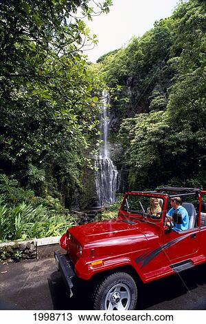 Stock Image - Hawaii, Maui, Hana Highway, Couple In Rental Jeep, View Waterfall Scenic Drive. Fotosearch