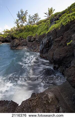 Stock Photograph - Hawaii, Maui, Hana, The rocky coastline of Waianapanapa showing the movement of the water.. Fotosearch