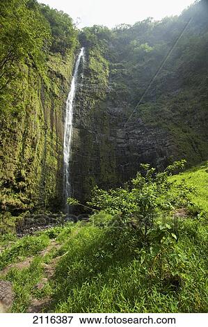 Stock Photo - Hawaii, Maui, Hana, Waimoku Falls surrounded by lush greenery and rocks.. Fotosearch