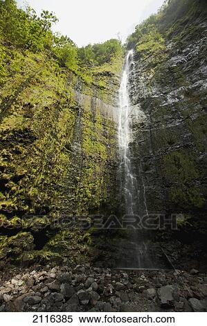 Stock Photography - Hawaii, Maui, Hana, Waimoku Falls surrounded by lush greenery and rocks.. Fotosearch