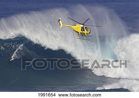 Picture - Hawaii, Maui, Helicopter Filming Tow-In Surfer At Peahi Aka Jaws, Wild Crashing Waves.. Fotosearch