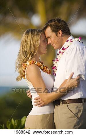 Stock Image - Hawaii, Maui, Honeymoon Couple Holds Each Other Close Under Palm Trees. Fotosearch