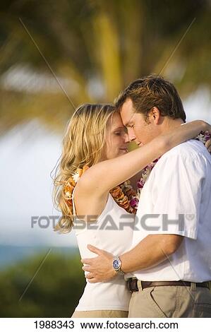 Stock Image - Hawaii, Maui, Honeymoon Couple Holds Each Other Close Under Palm Trees. Fotosearch
