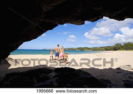 Stock Photograph - Hawaii, Maui, Kapalua, Fleming Beach, Family On Vacation Walking Down The Beach, View From Seacave. Fotosearch