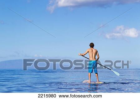 Stock Image - Hawaii, Maui, Kihei, Young man Stand Up Paddling in the ocean on sunny day.. Fotosearch