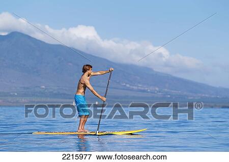 Hawaii, Maui, Kihei, Young man Stand Up Paddling in the ocean on sunny day. View Large Photo Image Stock Photo - Hawaii, Maui, Kihei, Young man Stand Up Paddling in the ocean on sunny day.. Fotosearch