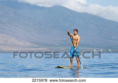Hawaii, Maui, Kihei, Young man Stand Up Paddling in the ocean on sunny day. View Large Photo Image Stock Photo - Hawaii, Maui, Kihei, Young man Stand Up Paddling in the ocean on sunny day.. Fotosearch