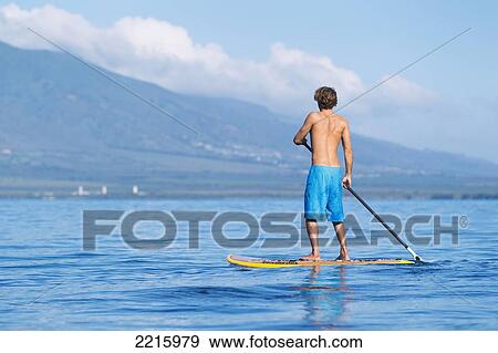 Stock Photo - Hawaii, Maui, Kihei, Young man Stand Up Paddling in the ocean on sunny day.. Fotosearch