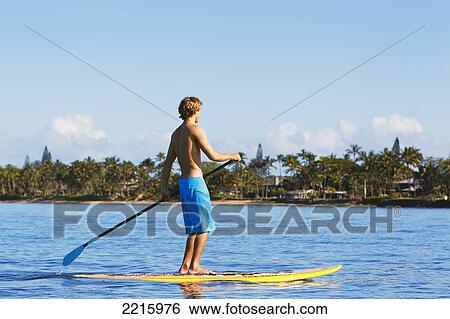 Stock Photograph - Hawaii, Maui, Kihei, Young man Stand Up Paddling in the ocean on sunny day.. Fotosearch