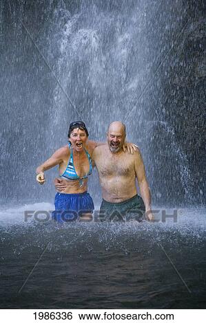 Stock Photograph - Hawaii, Maui, Kipahulu, Waimoku Falls, Older Couple Standing Under The Falls, Laughing.. Fotosearch
