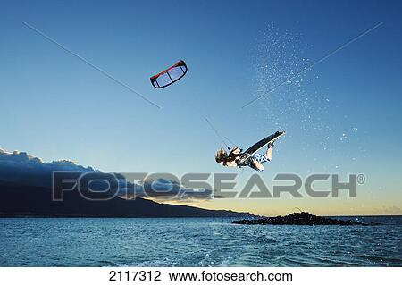 Stock Image - Hawaii, Maui, Kiteboarder gets airborne at sunset. EDITORIAL USE ONLY.. Fotosearch
