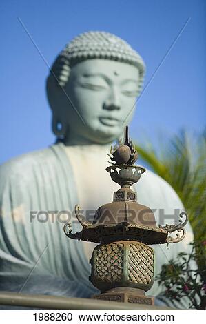 Stock Image - Hawaii, Maui, Lahaina Jodo Mission, Buddha Statue Blurred With Focus On Lantern In Foreground. Fotosearch