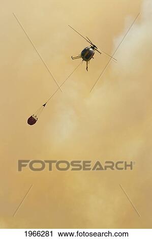 Hawaii, Maui, Ma'alaea, Fire Helicopter Carrying Water Bucket In Smoky Sky To Help Put Out Wildfire. Editorial Use Only. View Large Photo Image Stock Image - Hawaii, Maui, Ma'alaea, Fire Helicopter Carrying Water Bucket In Smoky Sky To Help Put Out Wildfire. Editorial Use Only.. Fotosearch
