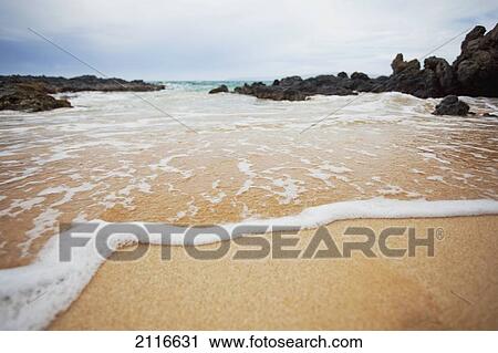 Stock Image - Hawaii, Maui, Makena, A closeup of the ocean over sand.. Fotosearch