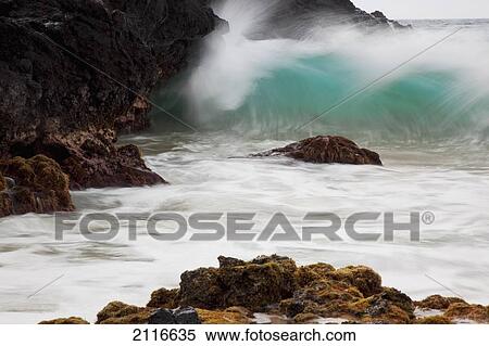 Stock Photography - Hawaii, Maui, Makena, An ocean wave crashes among a lava coast.. Fotosearch