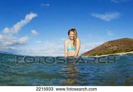 Stock Image - Hawaii, Maui, Makena Beach, A young woman enjoys taking a dip in the ocean on a sunny day.. Fotosearch