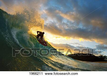 Stock Image - Hawaii, Maui, Makena - Big Beach, Skimboarder Carving Turquoise Wave, Sunset Light.. Fotosearch