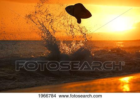 Picture - Hawaii, Maui, Makena, Skimboarder Gets Big Air Off A Wave At Sunset. Fotosearch