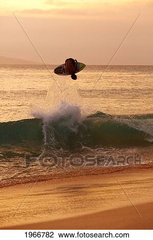 Stock Image - Hawaii, Maui, Makena, Skimboarder Gets Big Air Off A Wave At Sunset. Fotosearch