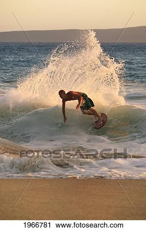Stock Image - Hawaii, Maui, Makena, Skimboarder Carves Big Turn On Wave At Sunset. Fotosearch